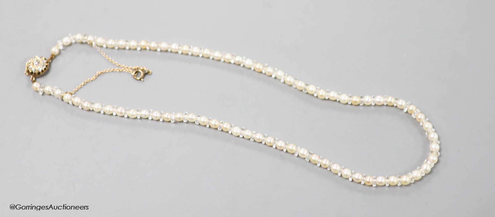 An early 20th century single strand cultured pearl and paste spacer necklace with diamond cluster set yellow metal clasp, 36cm, gross weight 10.7 grams.